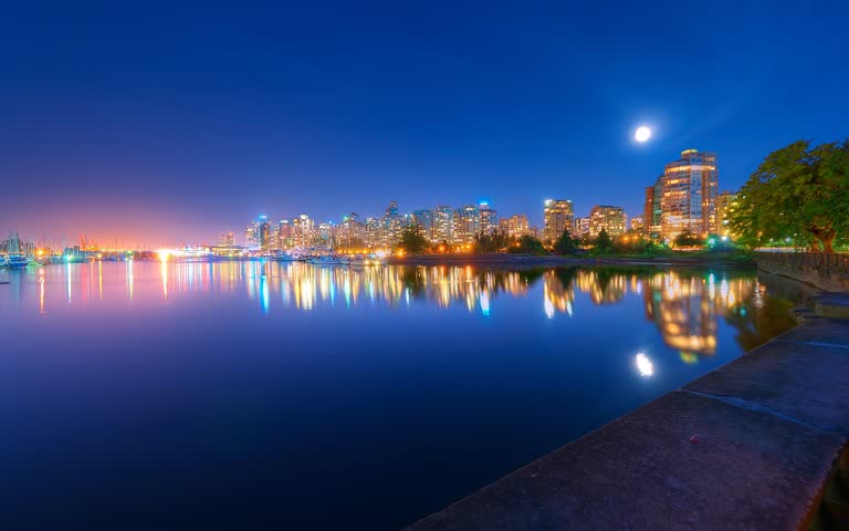 城市天际线的夜景,满月倒映在水中